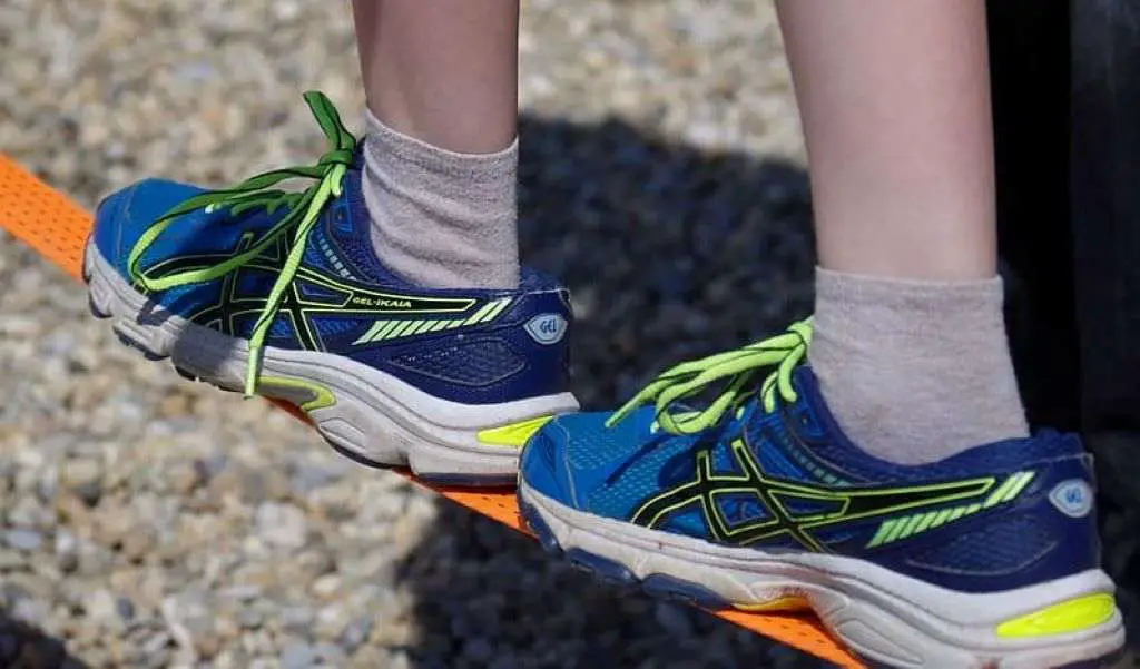 Person wearing blue green and white running shoes