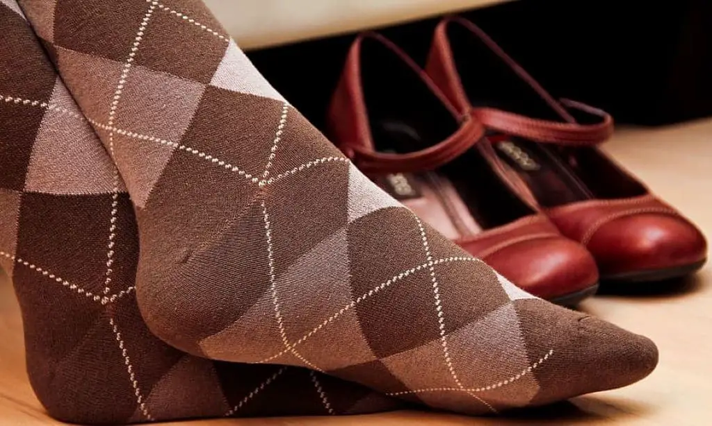 woman's feet beside red mary jane shoes