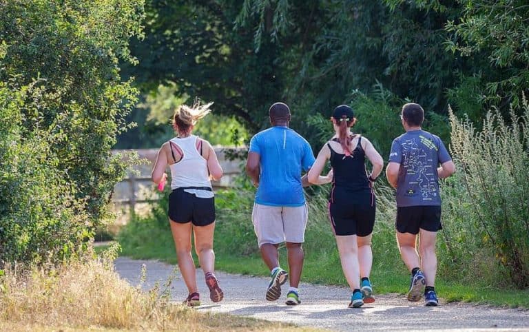 four people jogging in a park