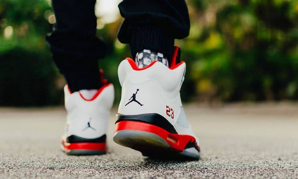 person wearing white black and red Air Jordan 5 shoes