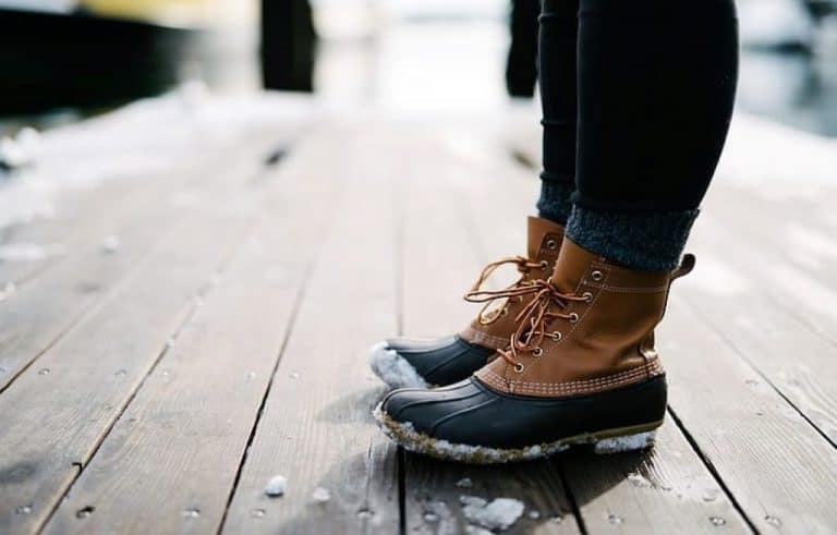 person in bean boots standing on brown wooden floor