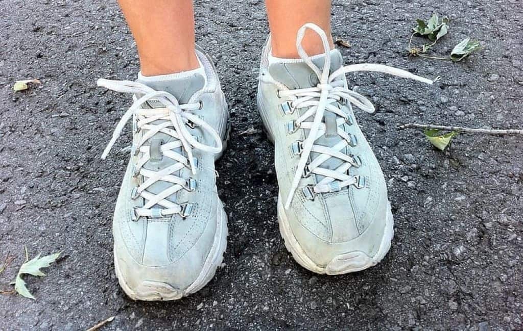 person's feet wearing blue and white running shoes